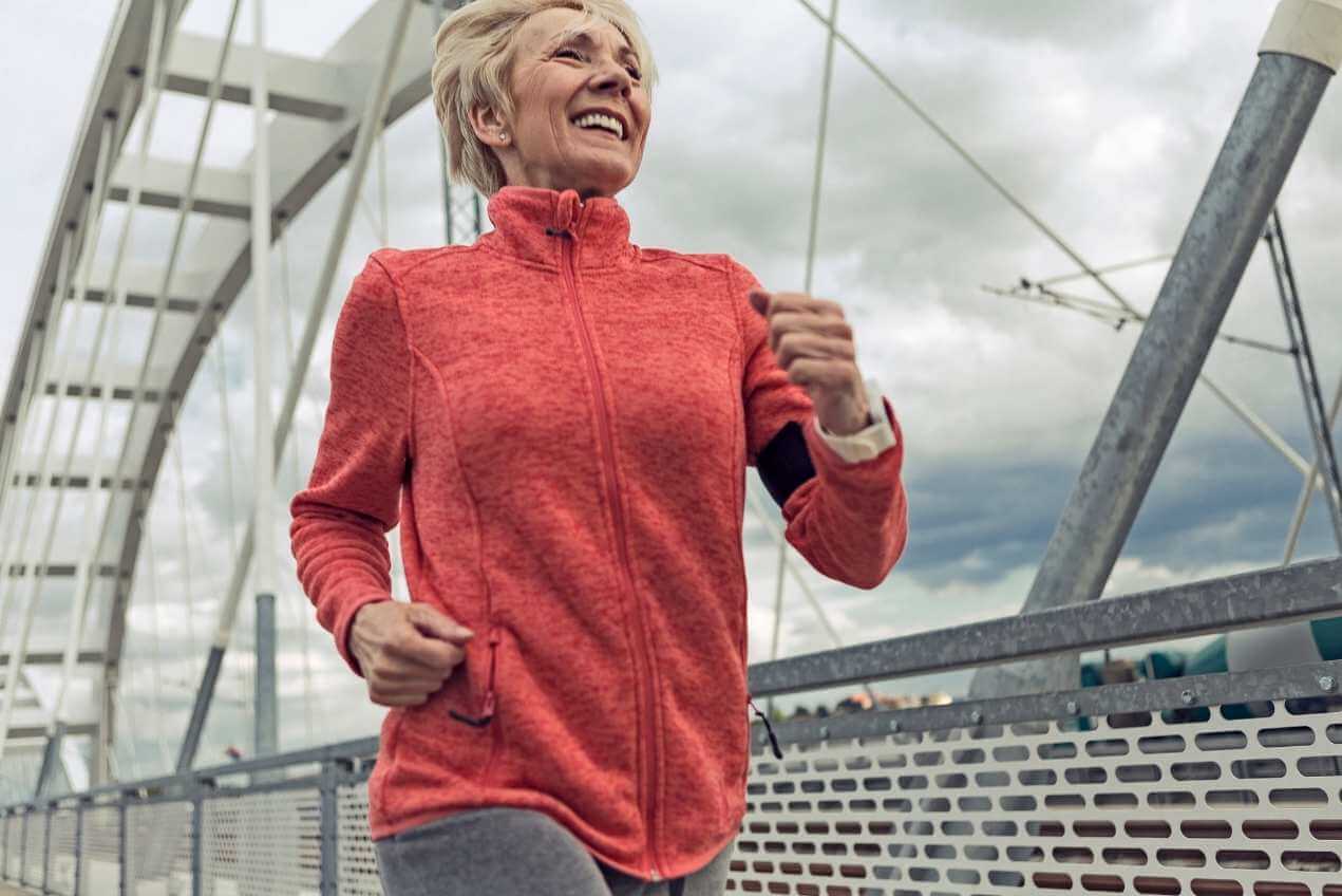 Older woman in red jumper smiling and running