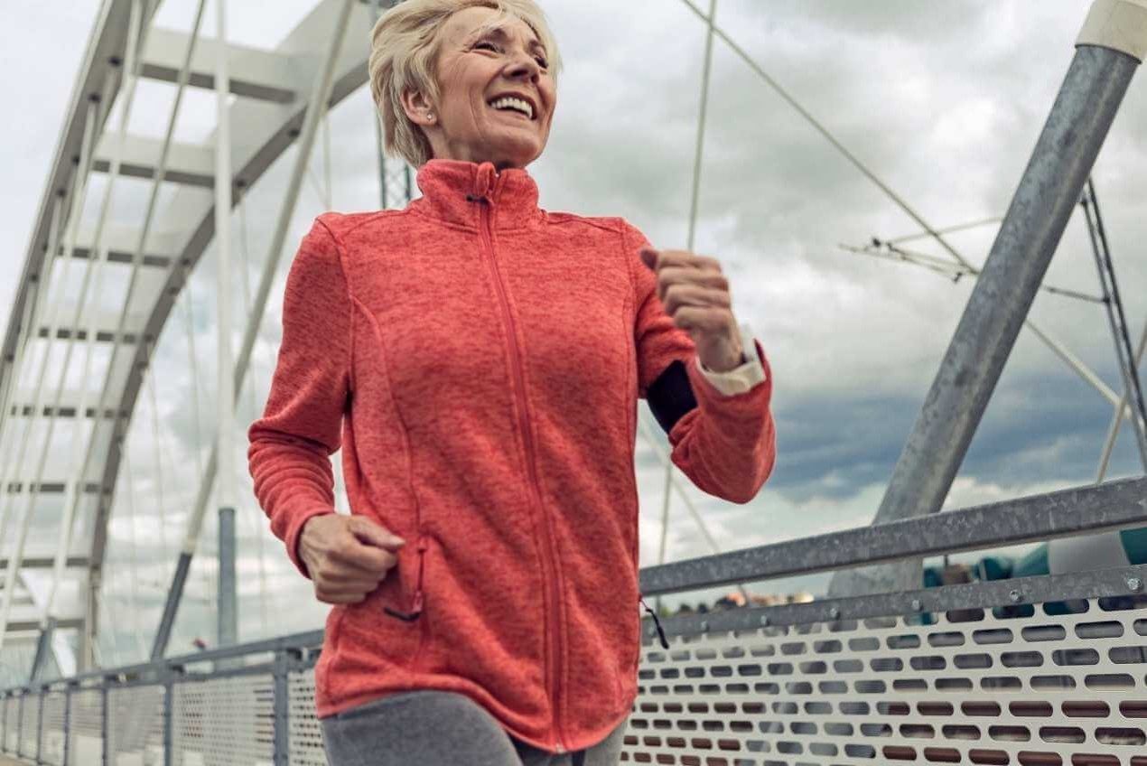Older woman in red jumper smiling and running