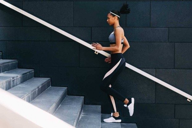 A young woman in activewear running up stairs