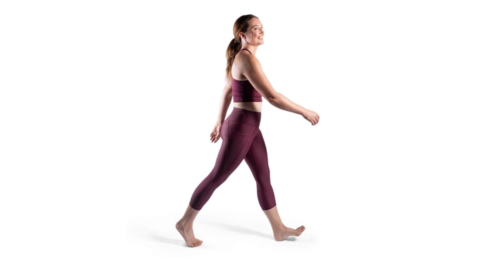 side on view of smiling woman in purple exercise gear walking