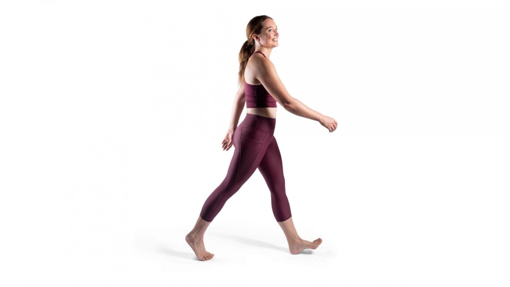 side on view of smiling woman in purple exercise gear walking