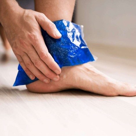 A man holding an ice pack against his painful ankle