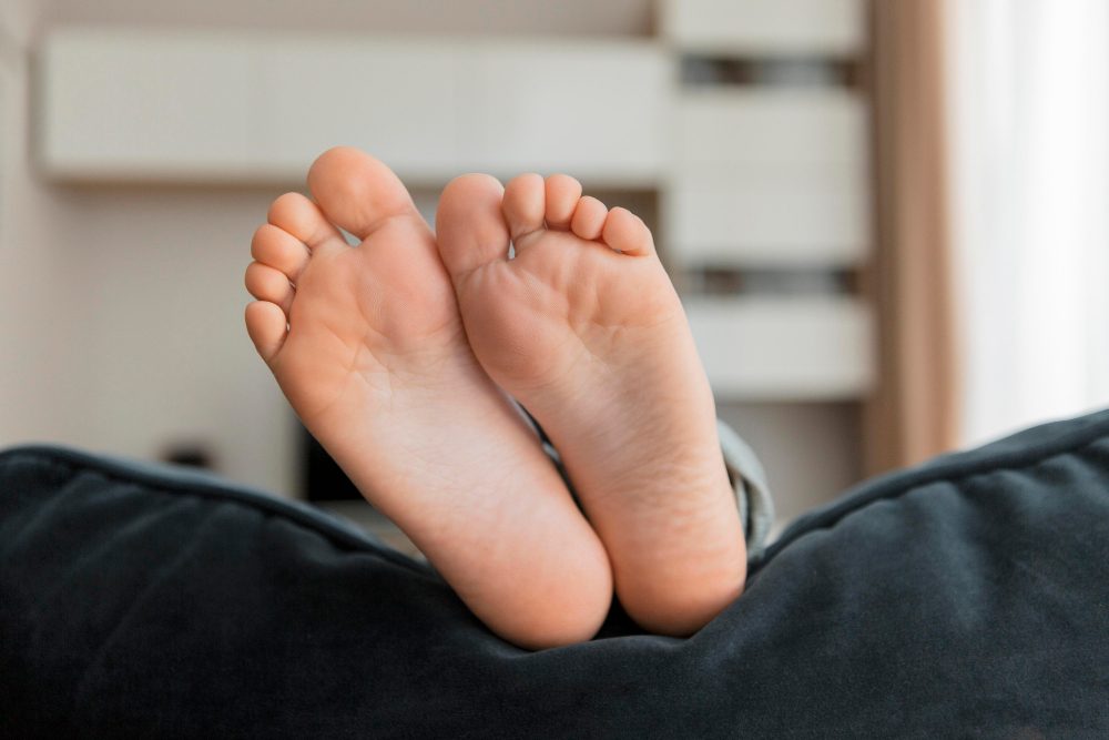 A side view of a foot with a hand holding the ankle. The ankle is highlighted red signifying pain