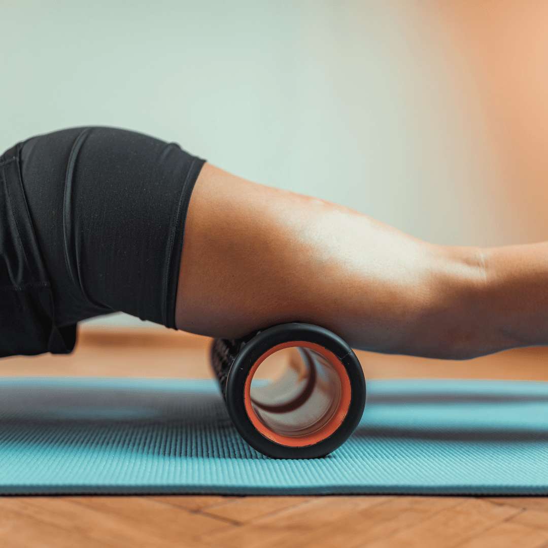 Woman's leg foam rolling front of her leg on yoga mat