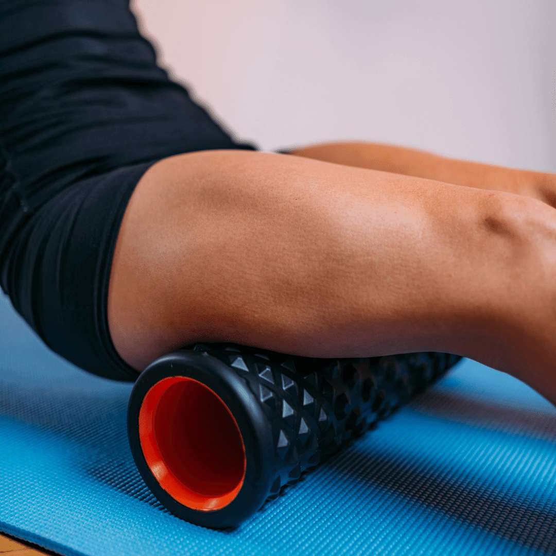 Woman's leg foam rolling back of her leg on yoga mat