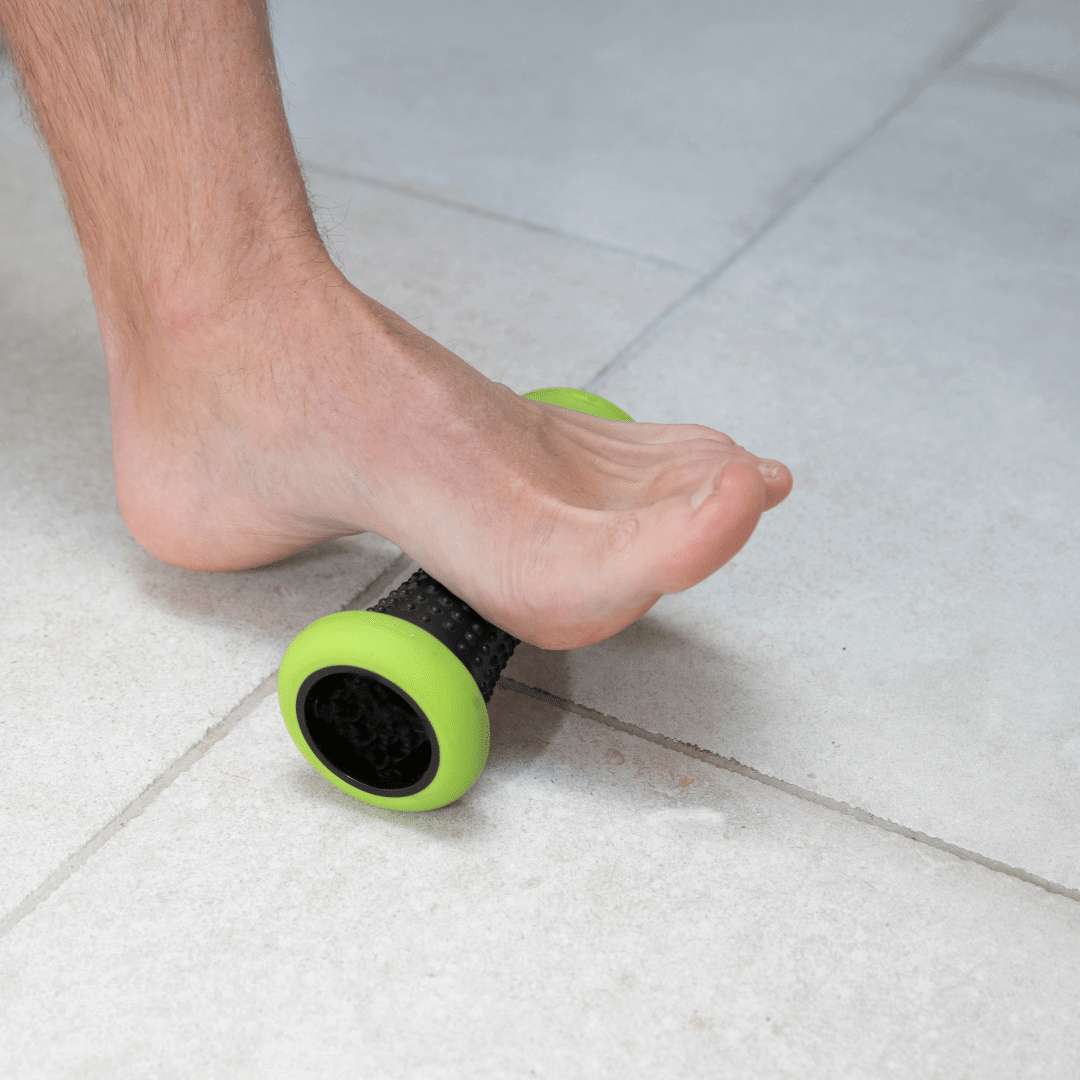 A man using a trigger point roller to massage the bottom of his foot