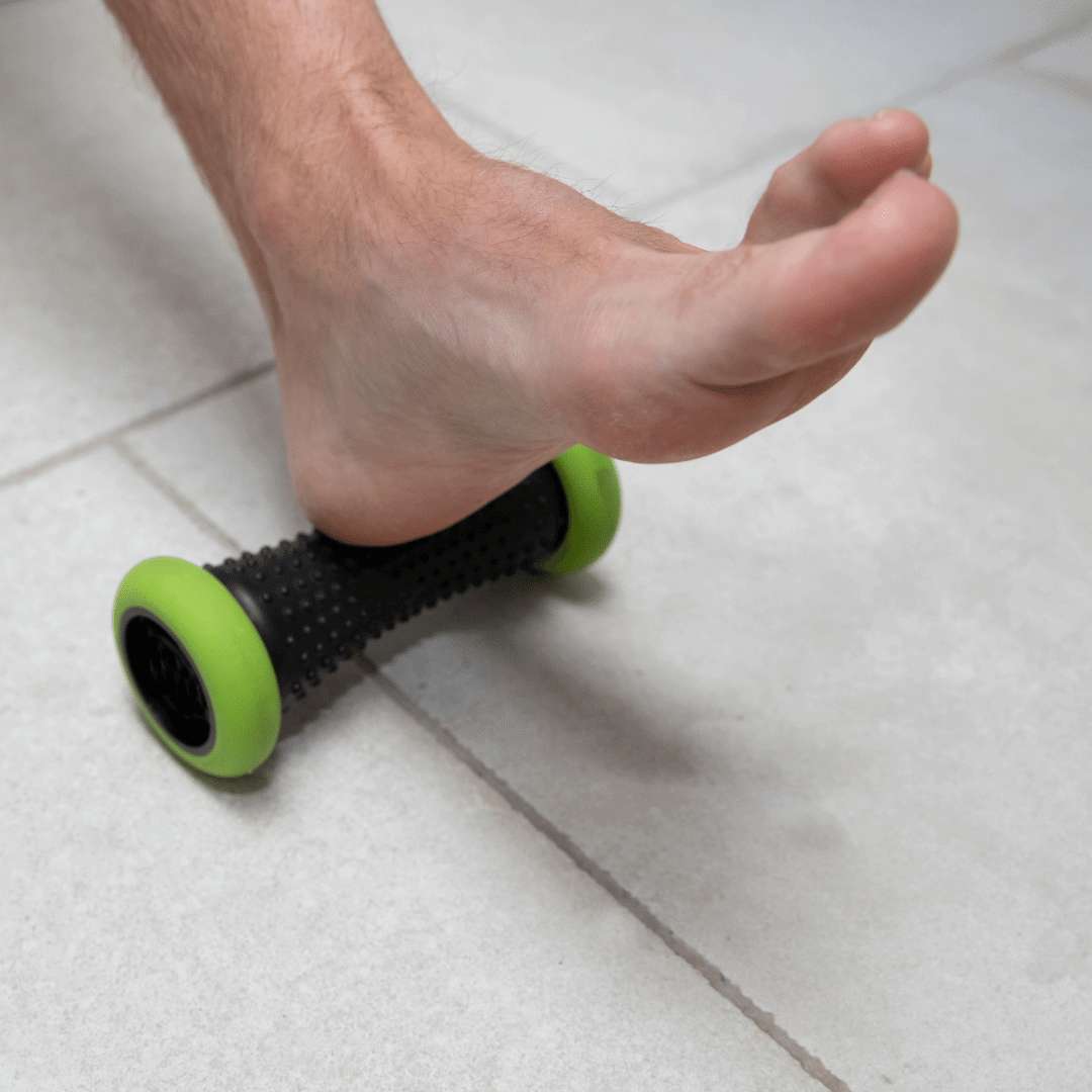 A man using a trigger point roller to massage the bottom of his foot
