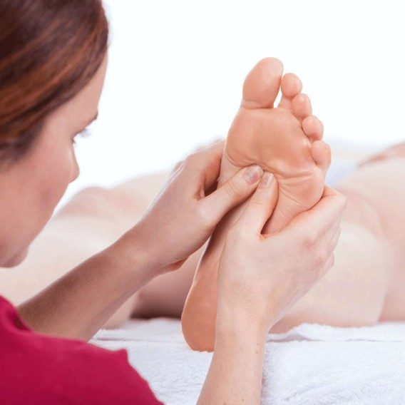A woman performing the plantar wart squeeze test on the bottom of a foot